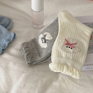 Detail of ruffled cuffs and plaid bow on knitted mid-calf socks with puppy embroidery