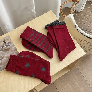 Close-up of deep red winter socks featuring vintage stripes, dots, and ruffle edge details