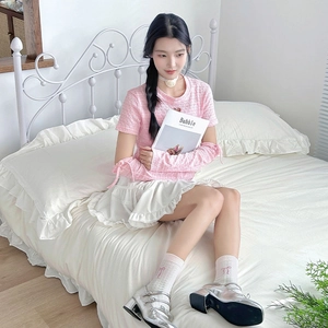 Calcetines blancos a media pantorrilla con lazo rosa mostrados por una modelo en cama.