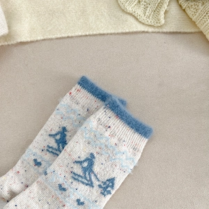 Detail of wool socks featuring skiing jacquard patterns and a soft plush blue cuff