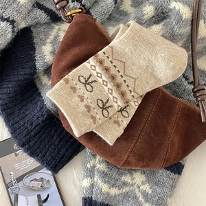 Gros plan de chaussettes en tricot beige à motifs de nœuds marrons et sac en daim