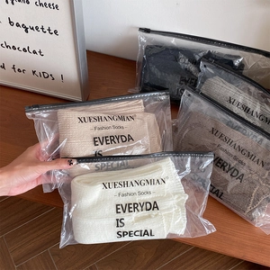 Detail of white knitted calf socks in branded zip-lock packaging with soft vertical ribs