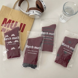 Detailed view of burgundy mid-calf socks with polka dots and stripes in gift packaging