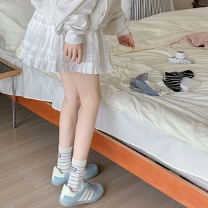 Detailed shot of striped cotton mid-calf socks paired with blue sneakers and skirt