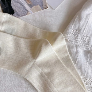 Detailed texture of cream-colored ribbed socks with delicate knit pattern and soft lace edge