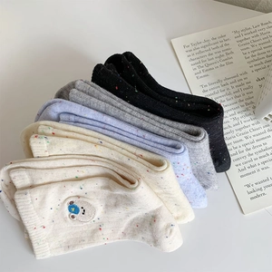Close-up of confetti knit socks featuring cute bear embroidery in various pastel colors