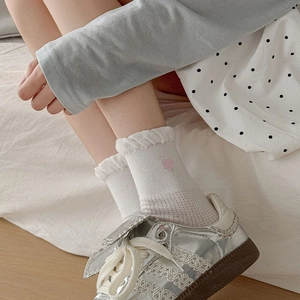 Detail of white ruffle socks with pink heart embroidery paired with vintage silver sneakers