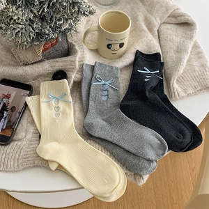 Three pairs of rib-knit socks with ribbon bows and blue heart embroidery accents