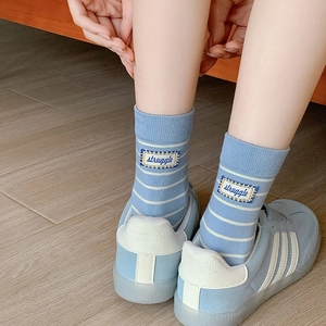 Close-up of blue striped cotton socks with 'struggle' patch and matching sneakers