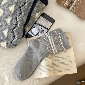 Détail de chaussettes en laine grise avec motif jacquard à nœud rose et tricot Fair Isle douillet