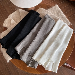 Detailed view of ribbed knit leg warmers in white, grey, and black on a wooden table