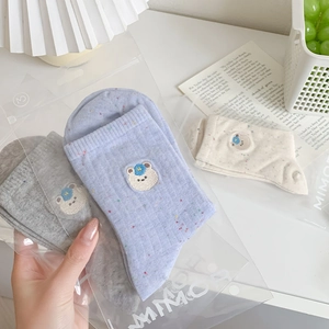 Detail of cute bear embroidery and colorful polka dot socks in branded packaging