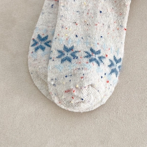 Close-up of Fair Isle wool socks featuring blue snowflake patterns and colorful speckled yarn