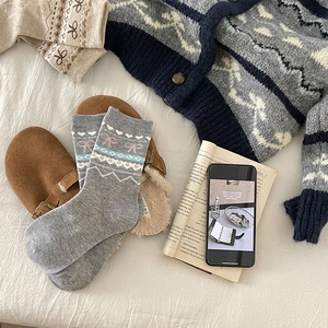 Gros plan de chaussettes en laine Fair Isle avec nœuds roses dans une ambiance d'hiver