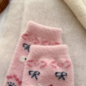 Close-up of pink plush thermal socks with navy bows and heart patterns for winter
