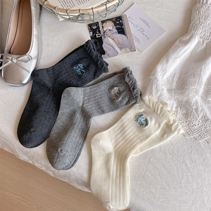 Detailed view of three-pack frill trim crew socks featuring Be Nice blue letter embroidery
