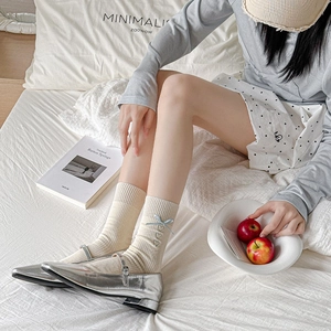 Detail of cream rib-knit socks with blue bow and heart embroidery, paired with silver shoes