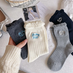 Detail of cotton crew socks featuring embroidered bow, Be Nice text and wavy lettuce trim