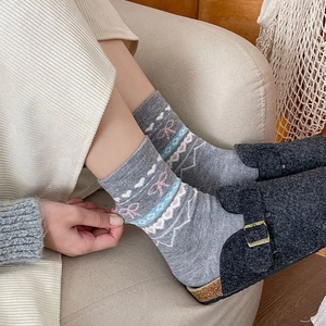 Gros plan de chaussettes en tricot Fair Isle avec nœuds roses et cœurs brodés
