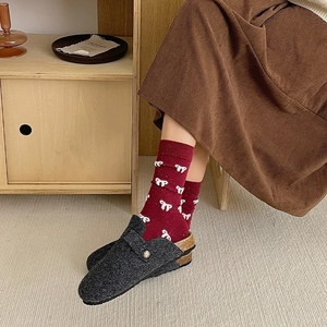 Close-up of felt clogs with gold buckle and festive red socks with white bows