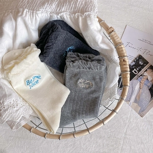 Detail of cotton socks with ruffled edges and Be Nice embroidery in a woven basket