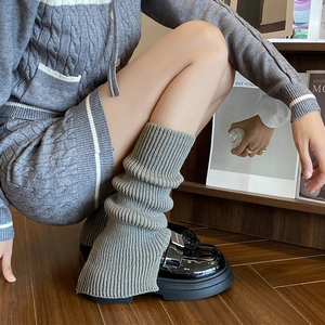 Close-up of grey knit leg warmers with ribbed texture and black platform loafers