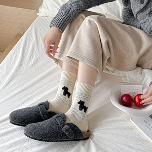 Detail of knit socks with horse motif and blue heart paired with wool felt mules