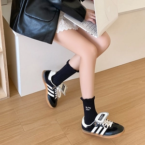 Close-up of black frilly mid-calf socks with Be Nice embroidery and classic sneakers