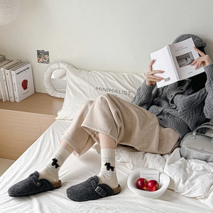 Detail of grey felt clogs with buckle and white knit socks featuring horse and heart patterns