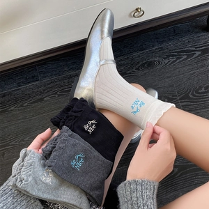 Detail view of cotton socks featuring 'Be Nice' bow embroidery and ribbed knit texture