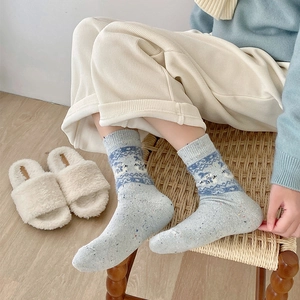 Detail of light blue wool socks with reindeer patterns and speckled knit texture