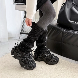 Detail of black knitted leg warmers paired with chunky platform sneakers and branded laces