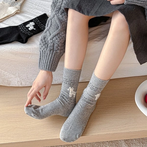 Close-up of grey knitted socks featuring cute white animal jacquard and heart textures