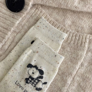 Détail de chaussettes crème avec motif chiot, confettis et broderie Love P élégante