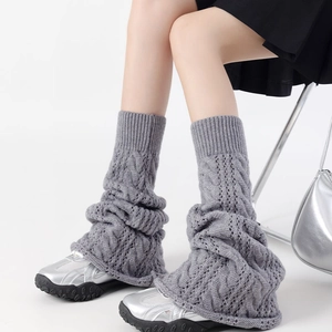 Close-up of grey cable-knit leg warmers with hollow patterns for a layered winter look