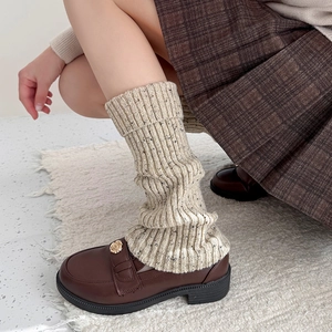 Detail of cream cable knit leg warmers with speckled yarn and leather loafers