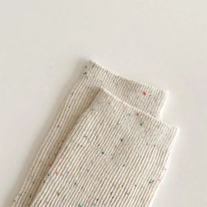 Close-up of ribbed cuffs on beige flecked knit socks with colorful speckled yarn detail