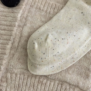 Gros plan de chaussettes en tricot beige avec points colorés et texture en coton