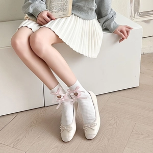 Detailed shot of white calf-high socks with pink ribbon bows and heart-shaped hollow patterns