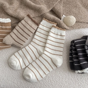 Macro detail of striped plush winter socks featuring warm coral fleece and wavy cuffs
