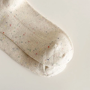Detailed macro view of beige ribbed knit socks with colorful flecks and smooth toe seams