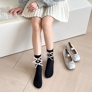 Detail of Lolita style black socks with pink velvet bows and openwork knitting design