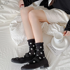 Close-up of black polka dot crew socks with frill trim styled with Mary Jane shoes