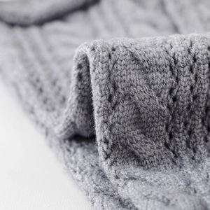 Macro shot of light gray cable knit texture on cozy winter leg warmers