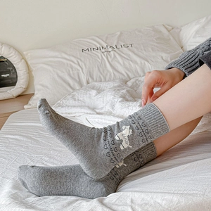 Dark gray crew socks with white poodle and heart knit patterns in a lifestyle setting