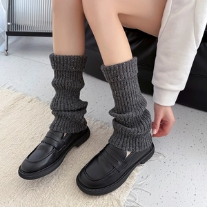 Detail of dark grey knit leg warmers with silver sparkles paired with black loafers
