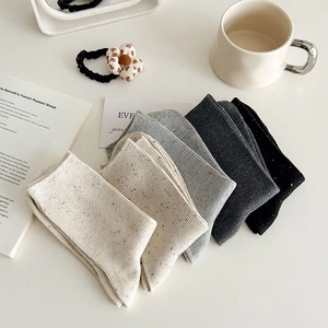 Close-up of four pairs of speckled cotton mid-calf socks in neutral vintage tones