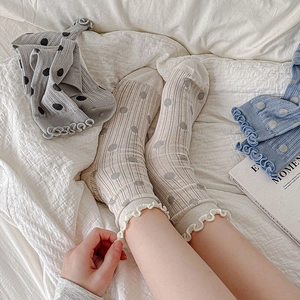 Close-up of ballet style frill trim socks with polka dots on white bedding background