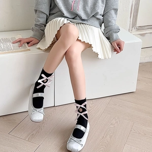 Close-up of Lolita black mid-calf socks with pink ribbon laces and silver Mary Jane shoes