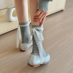 Close-up of grey knit mid-calf socks with white lace trim and ribbon bows on the back